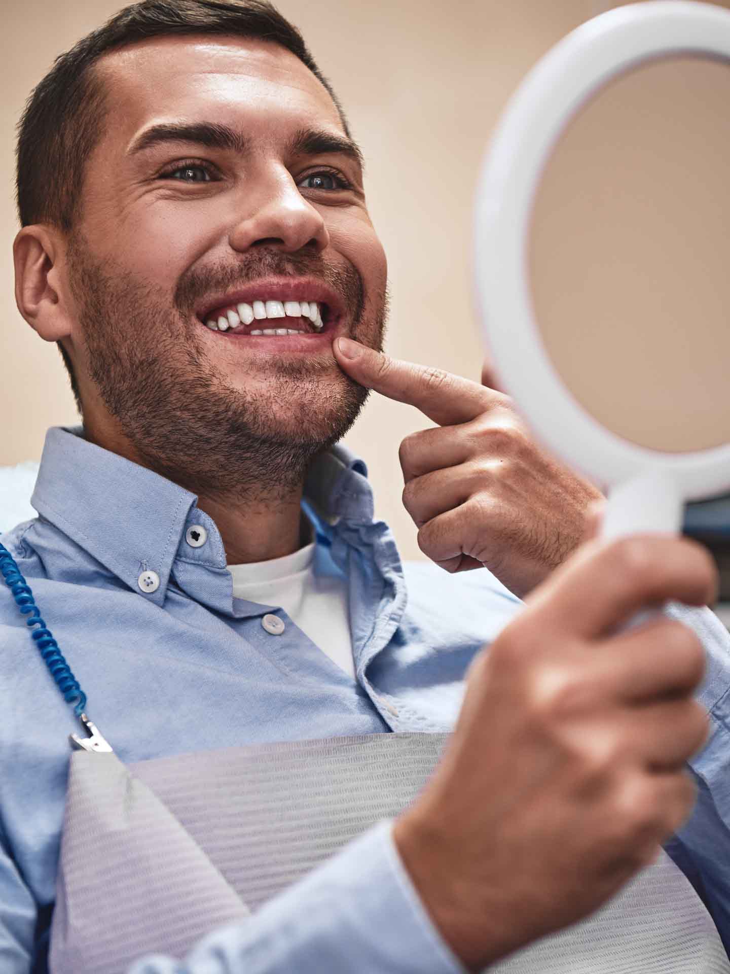 Man smiling while looking in a mirror during a cosmetic dental appointment