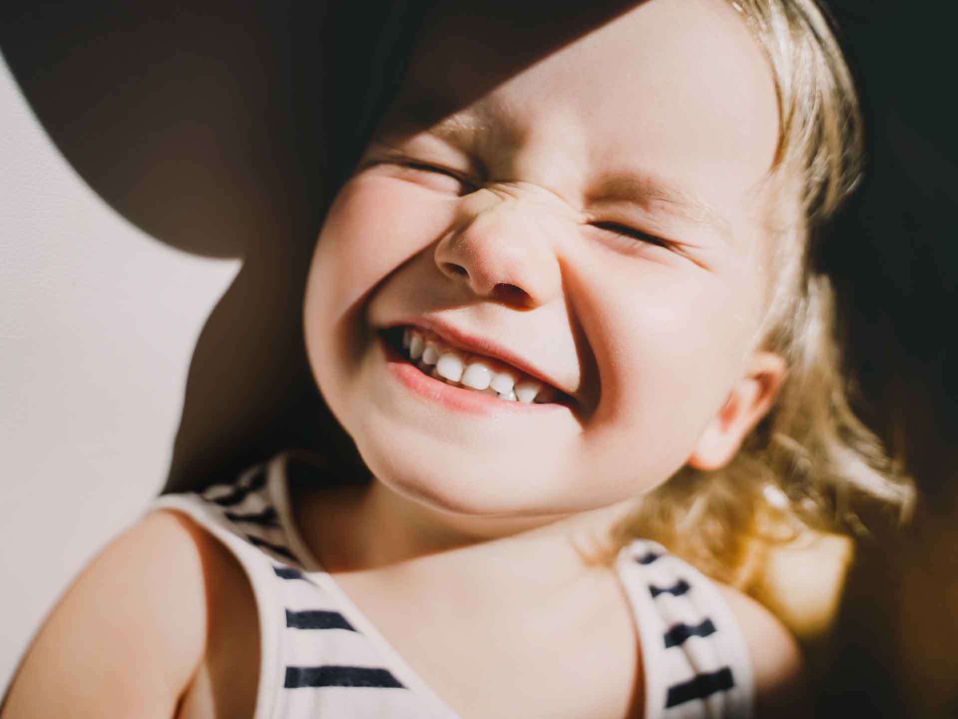 Young child smiling happily representing pediatric dentistry in Grand Blanc, Michigan