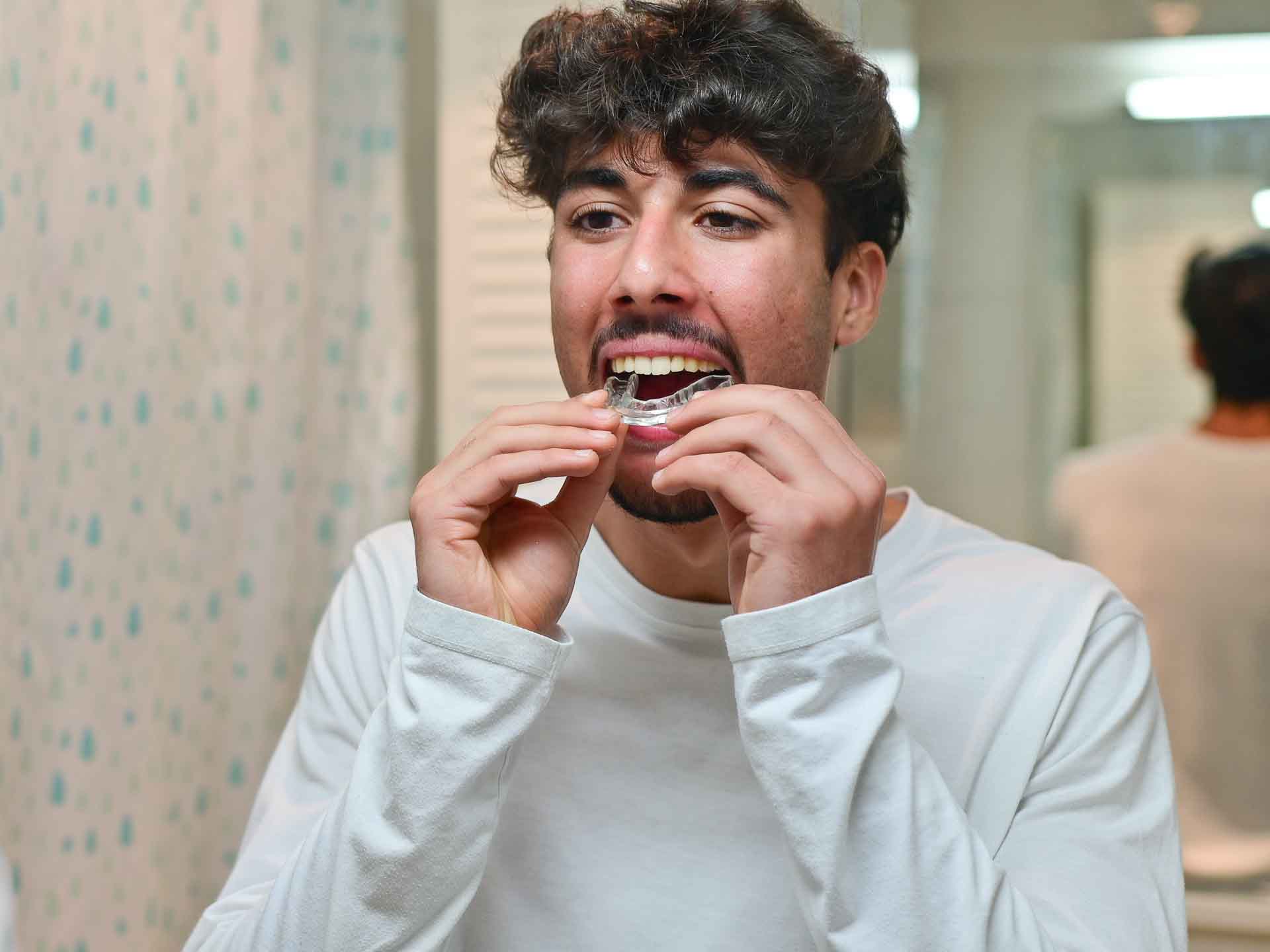 Young man putting in a clear aligner for SureSmile orthodontic treatment in Grand Blanc, Michigan